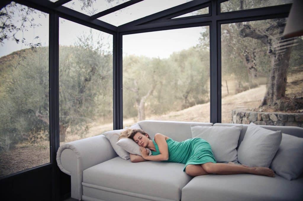 woman sleeping on a couch in front of windows