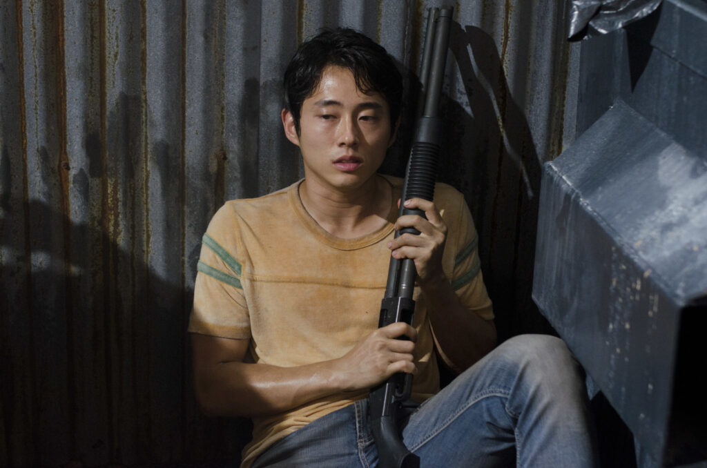 steven yeun glenn crouches with a shotgun