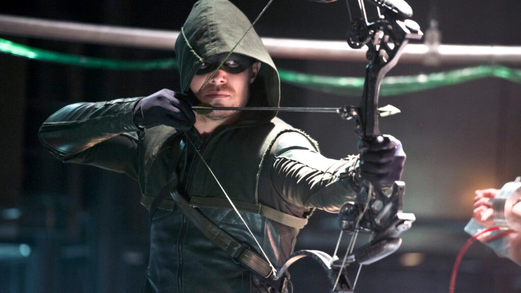 The Green Arrow, as played by Stephen Amell, points an arrow at his foe.