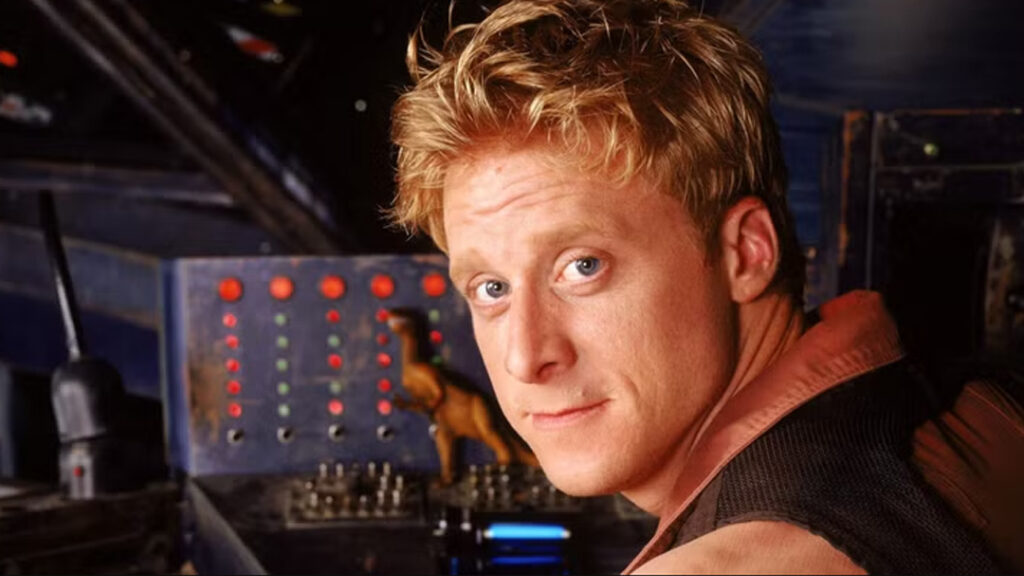 Wash seated in the cockpit of Serenity smiling, shortly before his sudden and shocking fiction death.