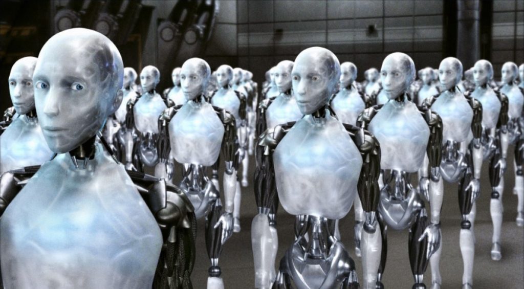 Sonny standing among rows of white humanoid robots in I, Robot.