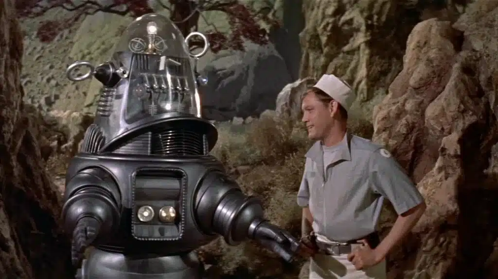 Robby the Robot from Forbidden Planet standing beside human characters. One of the first and most optimistic views of AI doom or p(doom).
