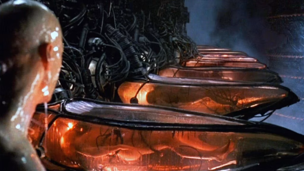 A human body suspended in a pod from The Matrix, surrounded by machine infrastructure. Iconic, and indicative of growing pessimism of AI doom or p(doom).
